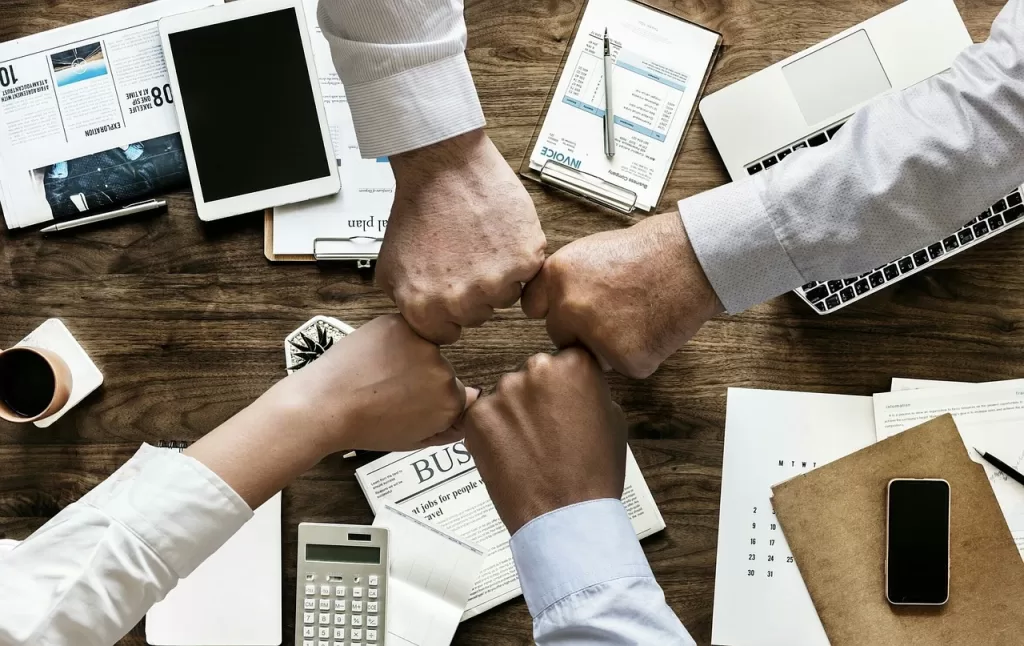 Team members bumping fists, representing teamwork and collaboration behind the mindset of rich people