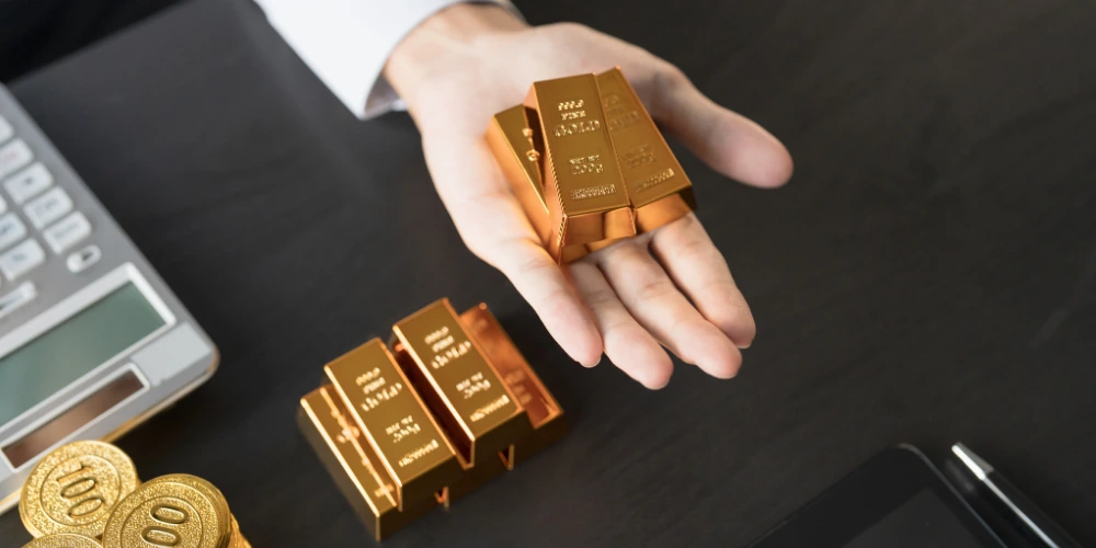 A hand holding gold bars showing the intention of investment in precious metals
